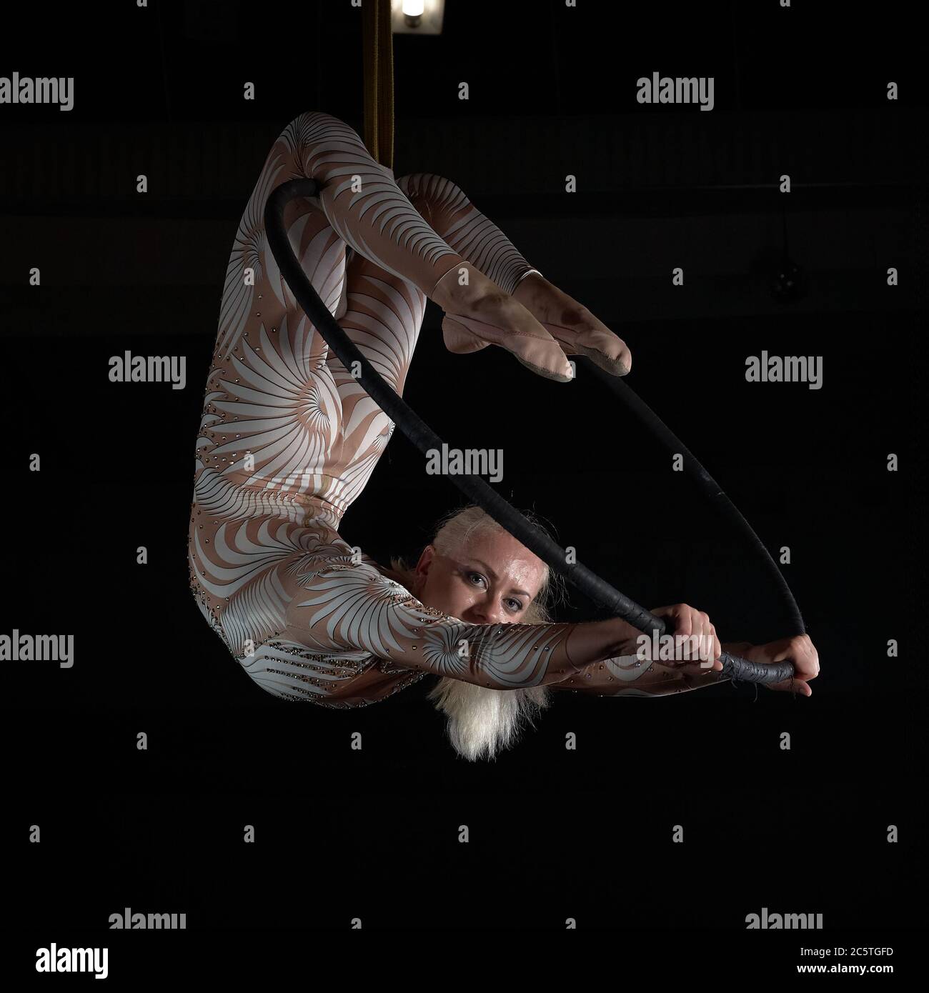 Der akrobat führt einen Stunt am Luftring durch. Mädchen in einem Anzug für Aufführungen. Stockfoto