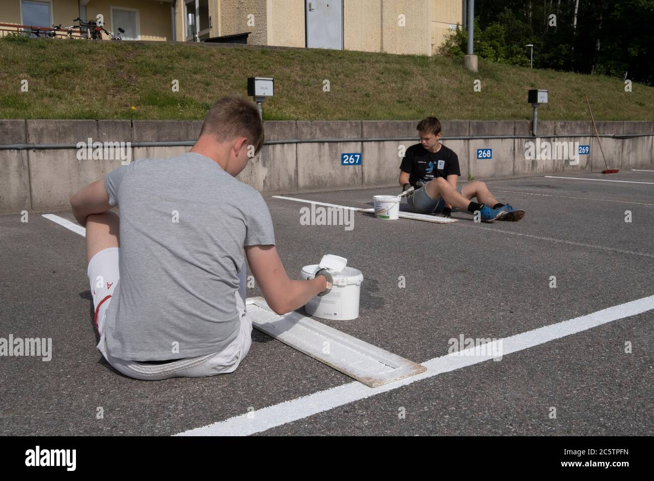 Junge Menschen haben im Sommer Arbeitsplätze zum Malen von Parkleinen gegeben. Stockfoto