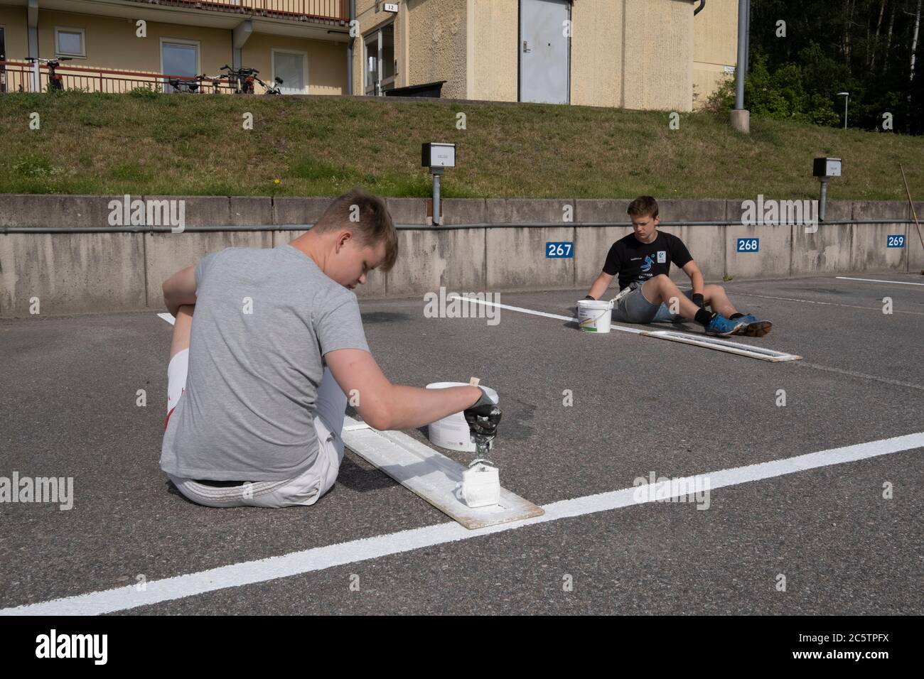 Junge Menschen haben im Sommer Arbeitsplätze zum Malen von Parkleinen gegeben. Stockfoto