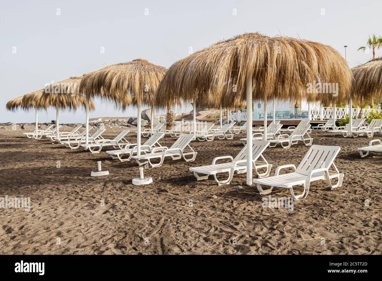 Costa Adeje, Teneriffa, Kanarische Inseln, Spanien. Juli 2020. Sonnenliegen und Strohschirme am Strand, da die ersten Touristen seit der Lockdo wieder ankommen Stockfoto