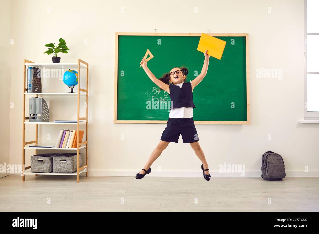 Zurück zur Schule. Fröhlich glücklich Schulmädchen springt bei einem Vortrag im Klassenzimmer. Stockfoto