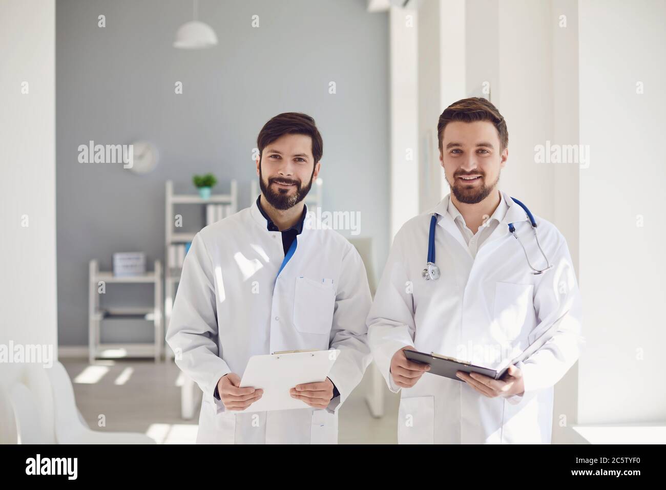 Zwei Praktizierende Ärzte mit Klemmbrett stehen in einem Klinikbüro. Stockfoto