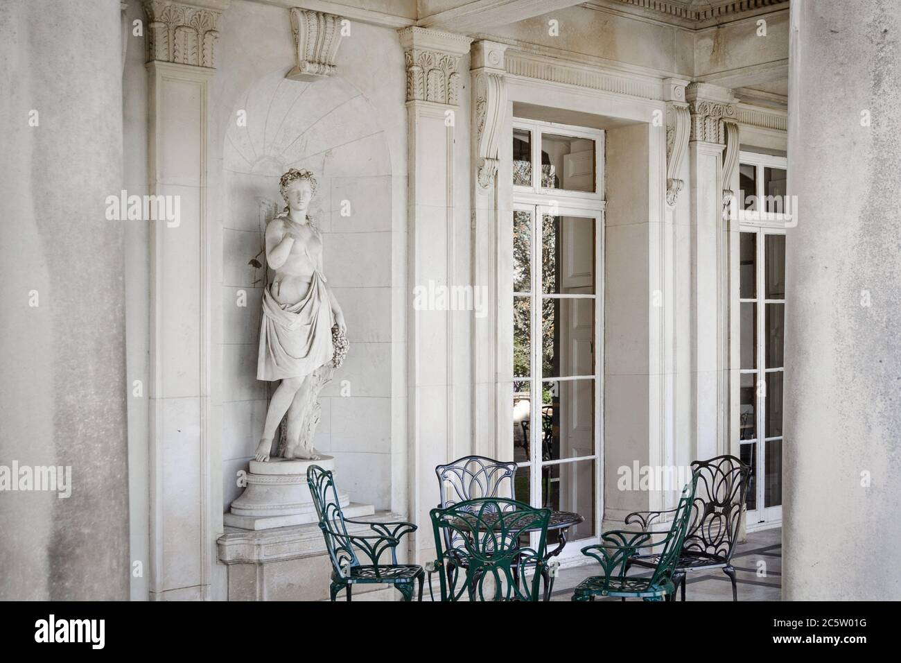 Griechische Statue einer Frau auf der Terrasse in der Nähe von Stühlen Und Tisch Stockfoto