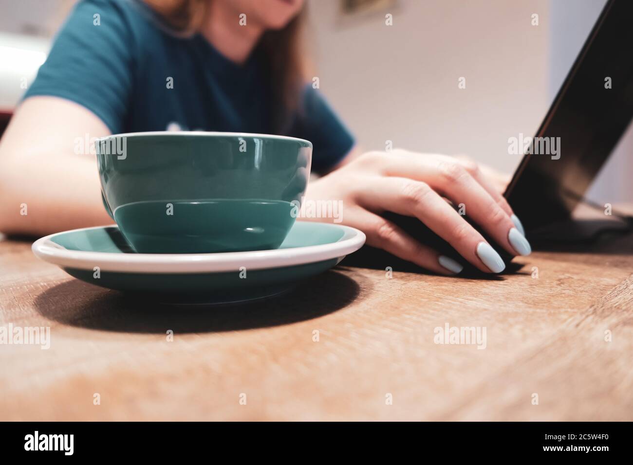 Seitenansicht einer Frau, die einen Laptop mit einer Tasse Kaffee benutzt Stockfoto