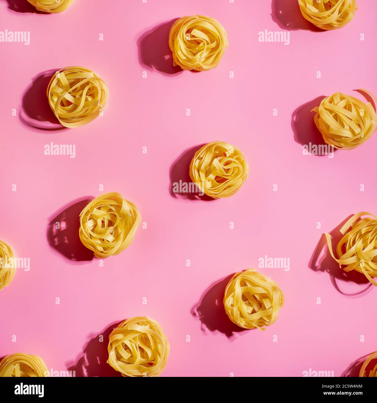 Pasta Art. Tagliatelle auf rosa Hintergrund in hartem Licht. Kreatives Layout mit Nudelnudeln, Draufsicht oder Flat Lay. Quadratisches Erntegut. Kreatives Design für Menü der italienischen Küche mit Kopierraum Stockfoto