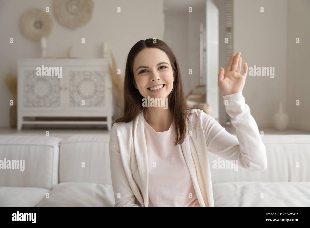 Kopf geschossen Porträt lächelnd schöne Frau winkt Hand an der Kamera Stockfoto