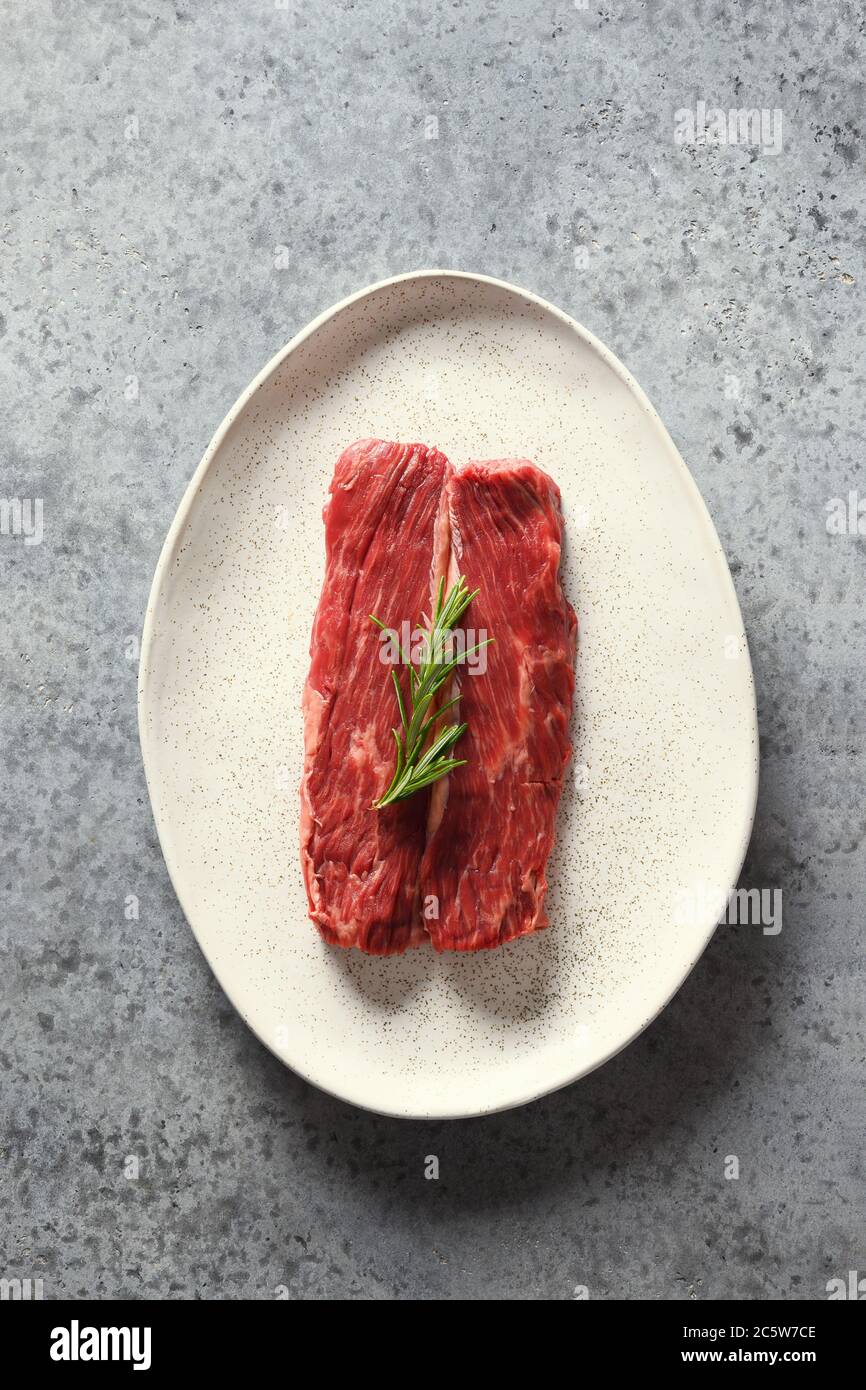 Rohes Ribeye Steak mit Rosmarin auf grau. Stockfoto