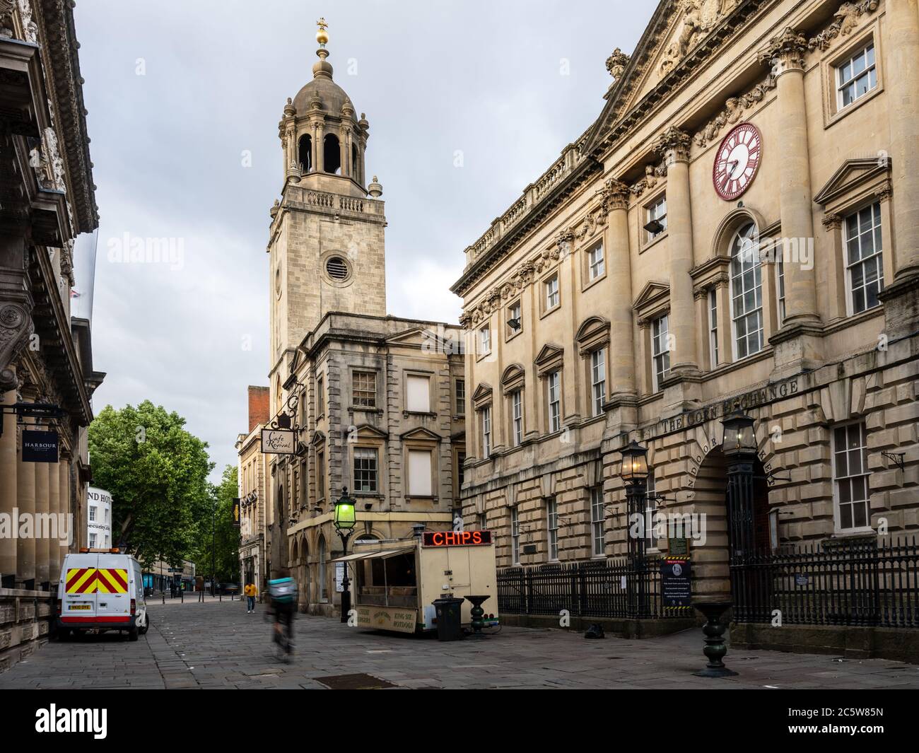 Ein Deliveroo Takeaway Radfahrer fährt an einem Burger van auf der Corn Street vor dem großen Georgian Corn Exchange Gebäude und All Saints Church in geparkt Stockfoto