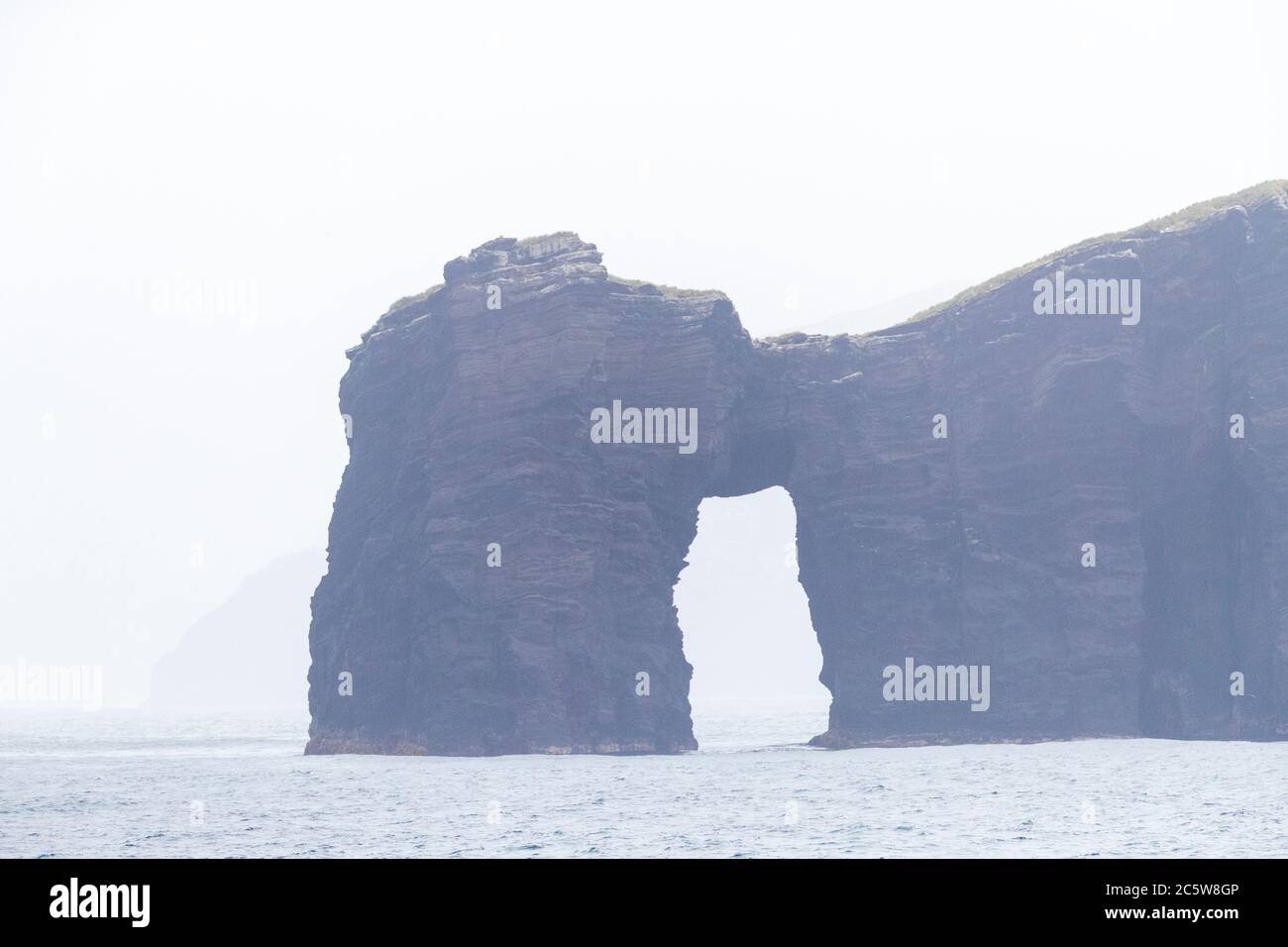Natürliche Gesteinsformation an der Küste der Antipoden-Inseln, Subantarktische Inseln Neuseelands. Naturbrücke. Während eines nebligen Tages. Stockfoto