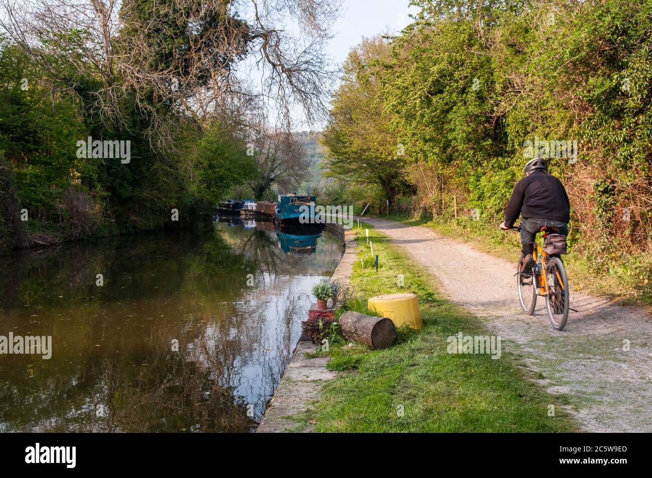 Bath, England - 19. April 2011: Ein Radfahrer, der vorbeifahrenden Boote auf dem Treidelpfad Kennet & Avon Canal in der Nähe von Bath in Somerset. Stockfoto