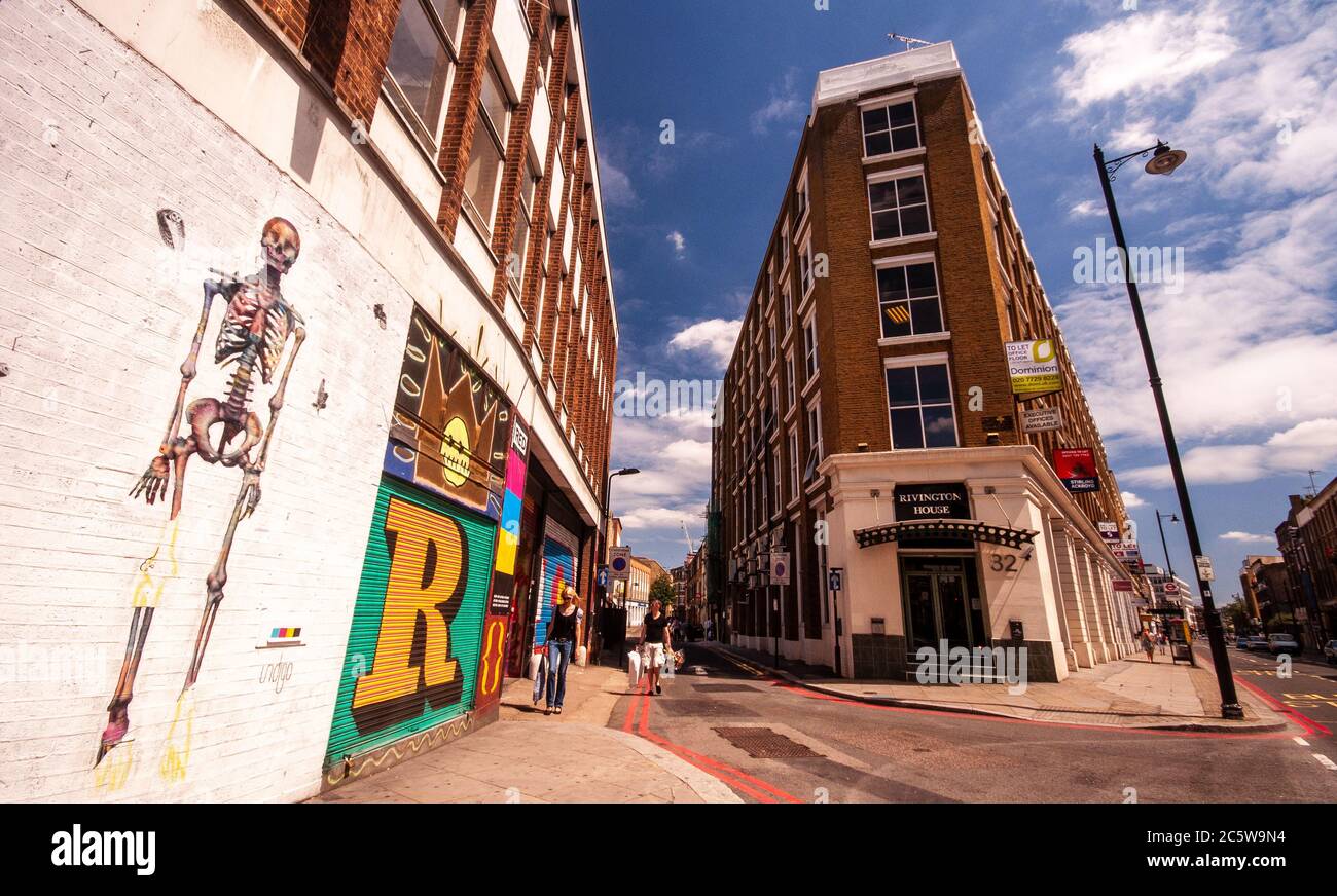 London, England, Großbritannien - 4. Juli 2010: Fußgänger gehen an Straßenkunst auf Gebäuden in der Rivington Street in Shoreditch, East London vorbei. Stockfoto