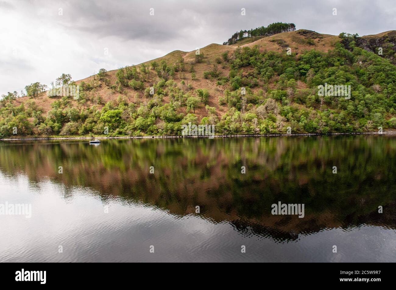 Ein kleines Fischerboot fährt durch das ruhige Wasser des Loch Awe Sees unter den Bergen der West Highlands von Schottland. Stockfoto