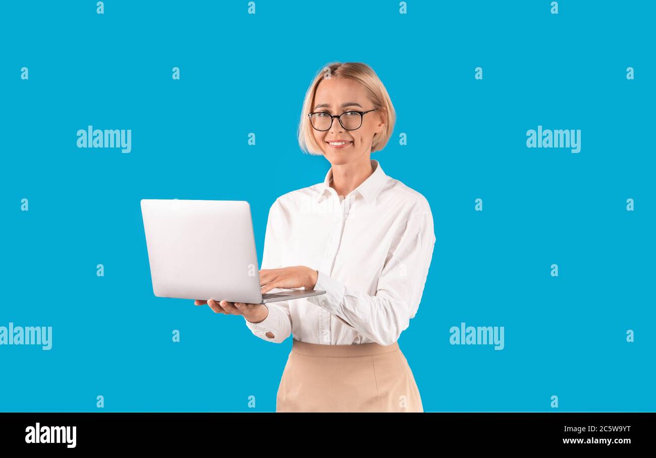 Online arbeiten. Erfolgreicher Büroangestellter mit Laptop-Computer auf blauem Hintergrund Stockfoto