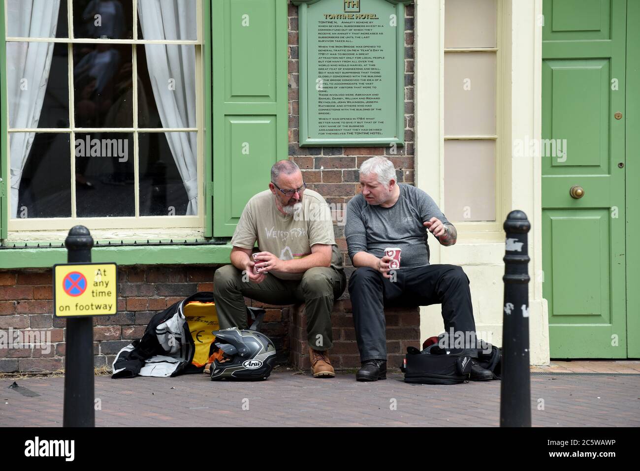 Zwei Motorradfahrer trinken einen Takaway Kaffee vor dem Tontine Hotel und Pub in Ironbridge, das wegen des Covid 19 Virus während der Sperre geschlossen wurde Stockfoto