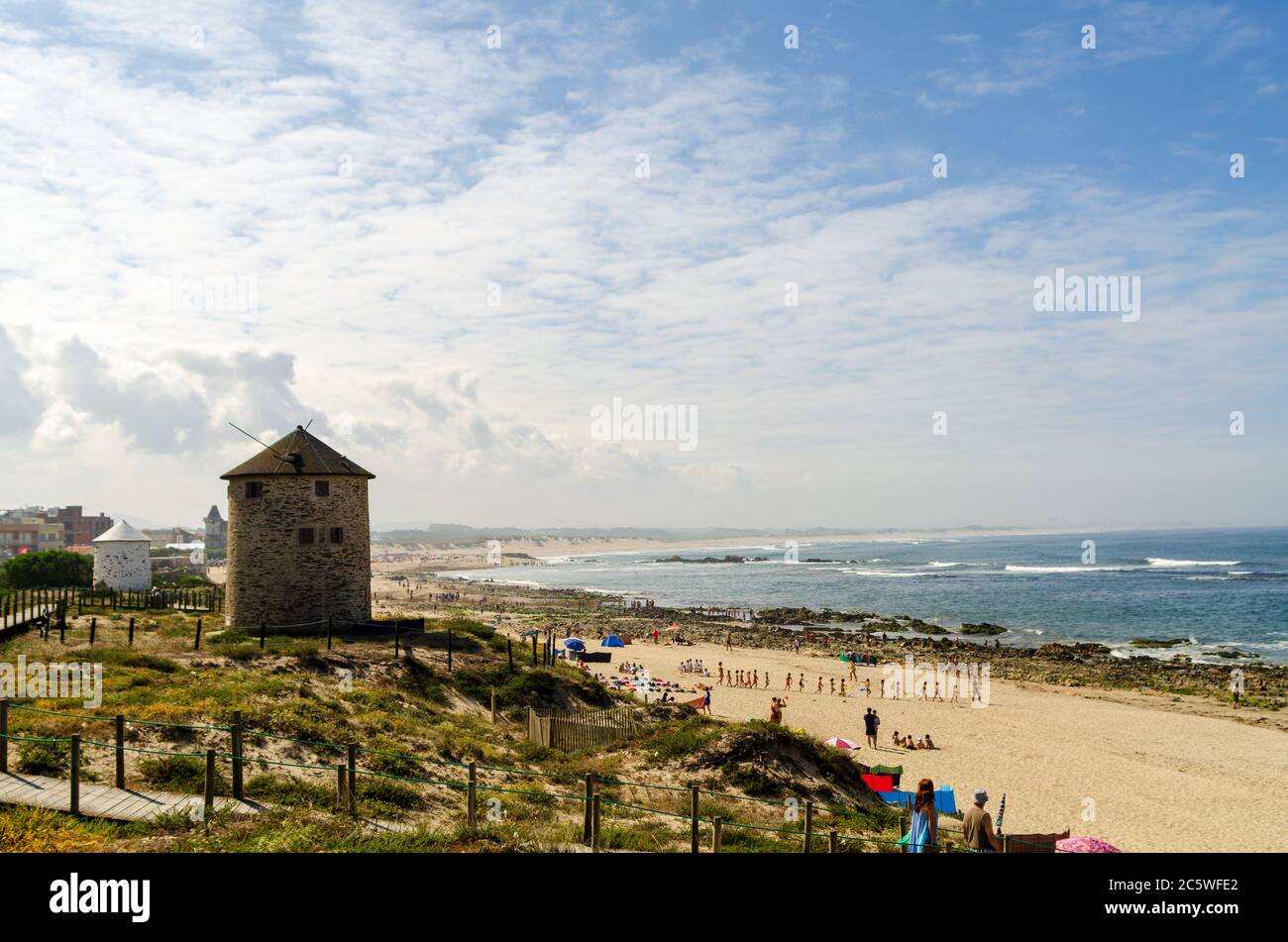 Portugiesische Mühle Häuser in den Dünen von einem Strand voll Von Touristen am Meer in Apulien während des sonnigen Sommers Wetter Stockfoto