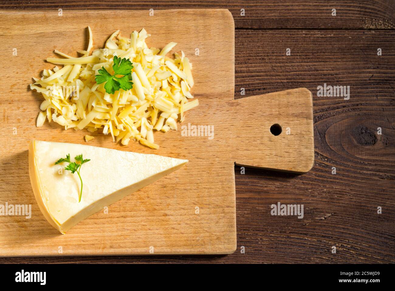 Geriebener Käse und Käse Dreieck mit Petersilie auf Schneidebrett auf Holztisch Stockfoto