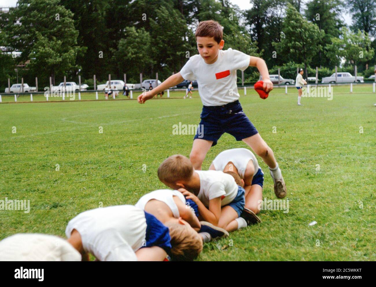 Schulkinder bei der Schule Sporttag in einem Park mit Jungen halten Bohnenbeutel springen über andere Kinder in einem Rennen, Internationale Schule, Hamburg, Deutschland in den 1960er Jahren Stockfoto