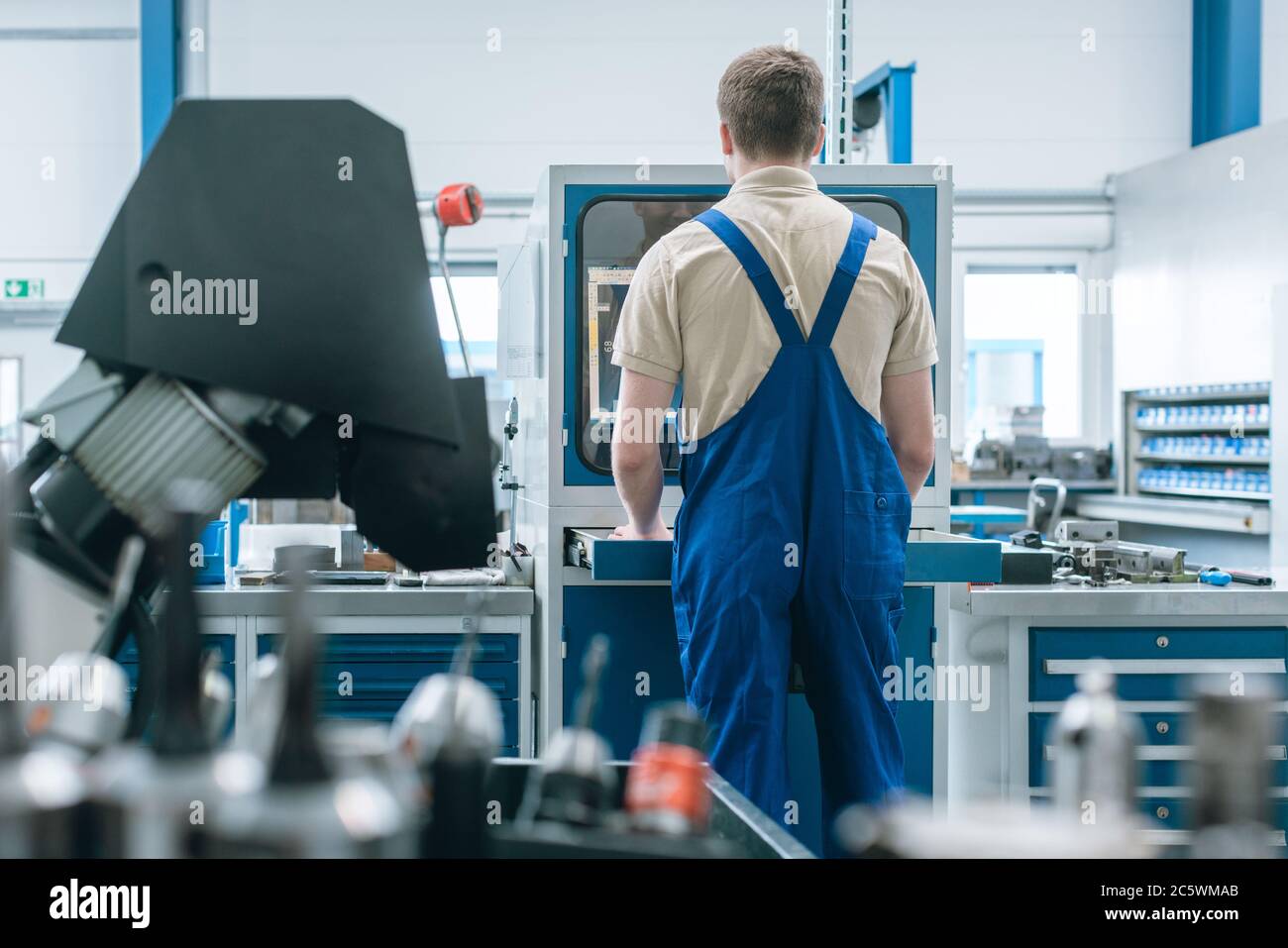 Mann, der in der Fabrik auf einer halbautomatischen Produktionslinie arbeitet Stockfoto