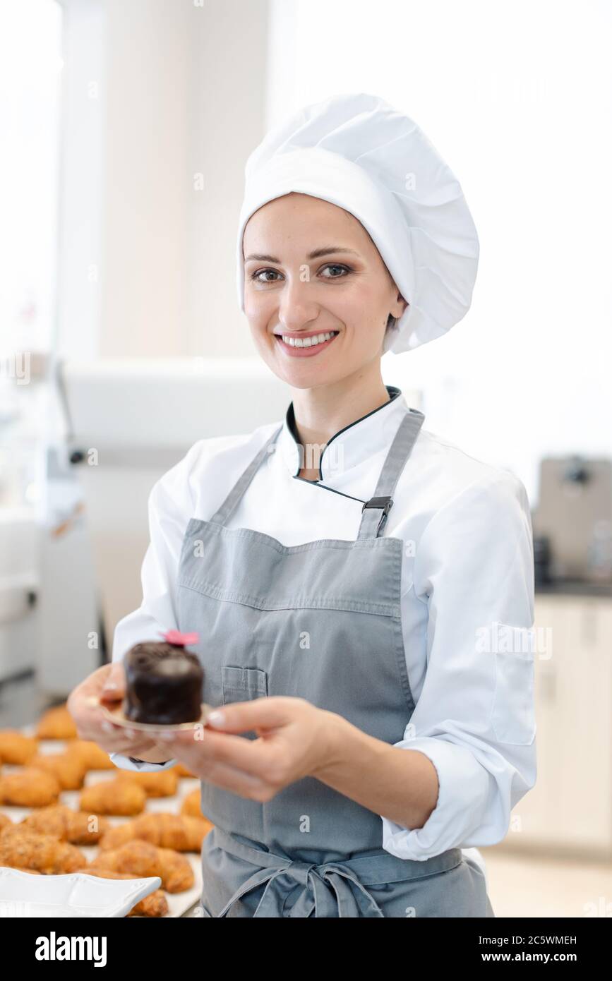 Konditor zeigt einige kleine Süßigkeiten und Kuchen, die sie gemacht hat Stockfoto