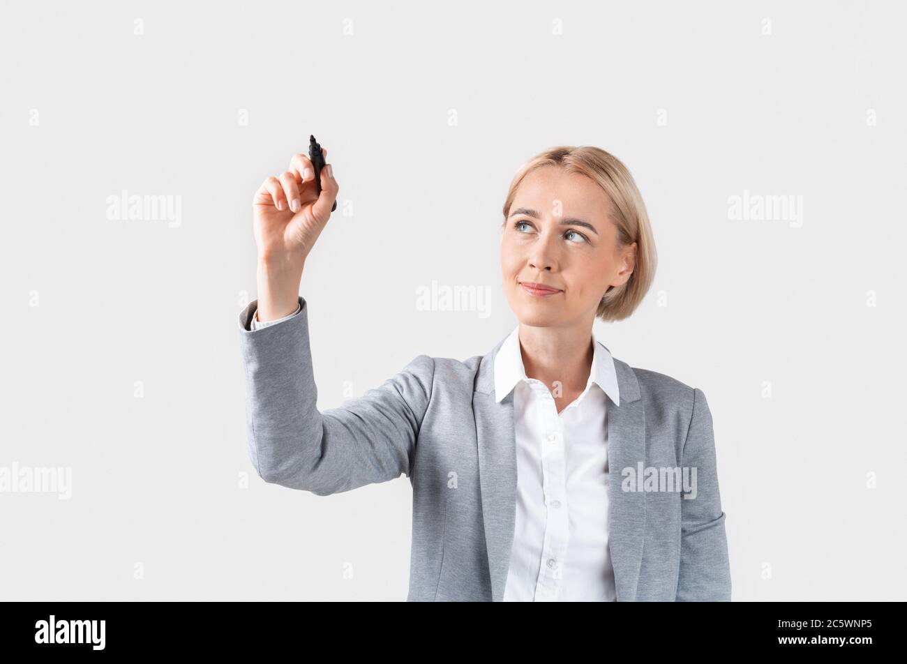Attraktive Geschäftsfrau Schreiben oder Zeichnen auf virtuellen Bildschirm vor hellem Hintergrund, Raum für Design Stockfoto
