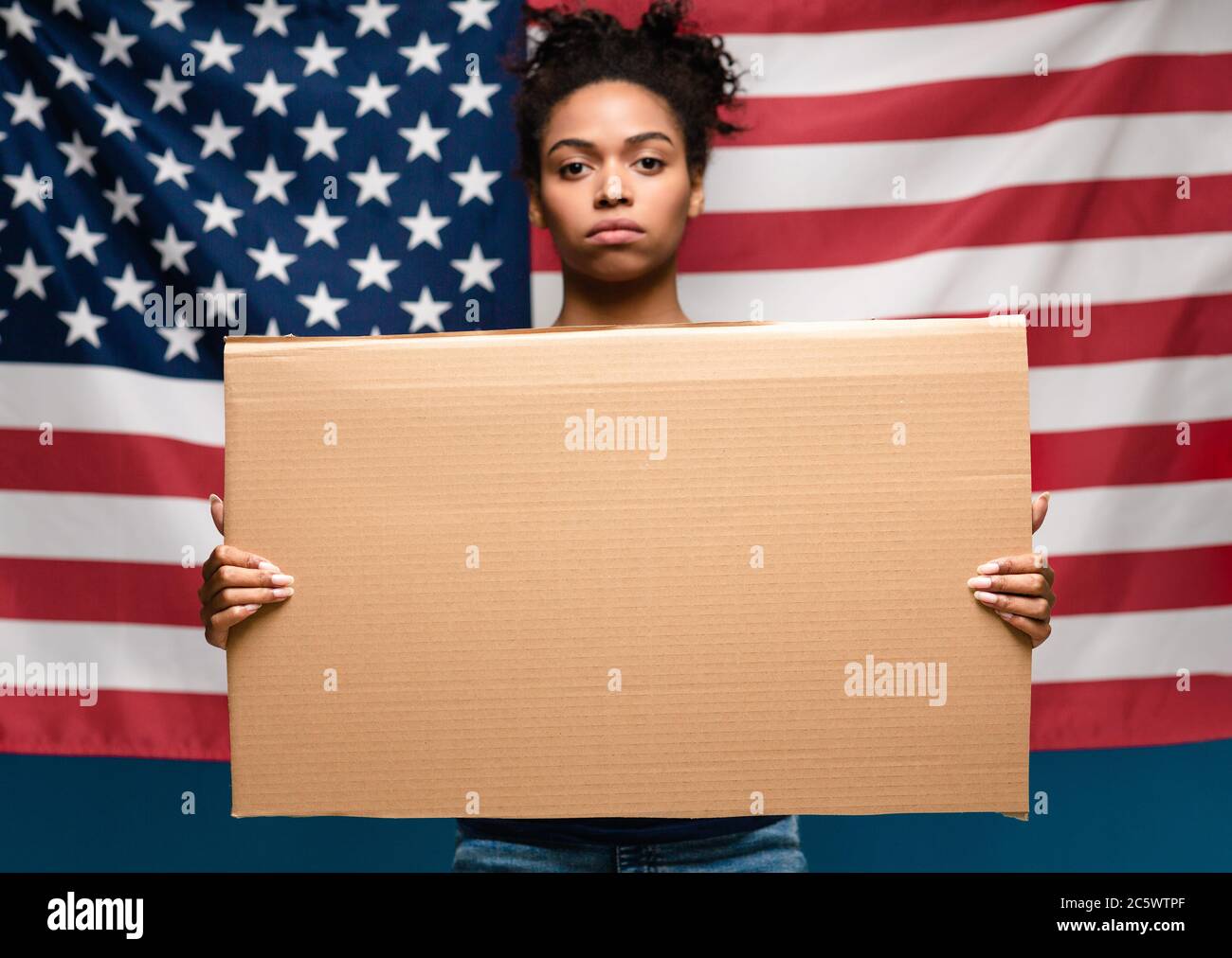 Schwarzes Mädchen mit leerem Karton über amerikanischer Flagge stehend Stockfoto