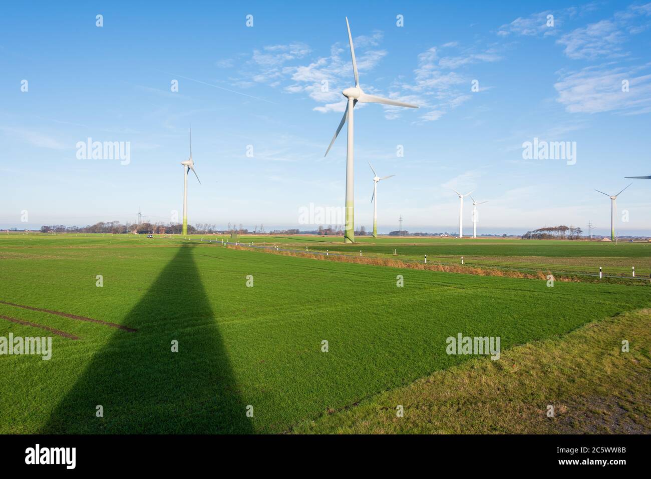 Windkraftanlagen zur ökologischen Stromversorgung sind in der windreichen ostfriesischen Küstenregion ideal zu betreiben. Im Hintergrund das Wattenmee Stockfoto