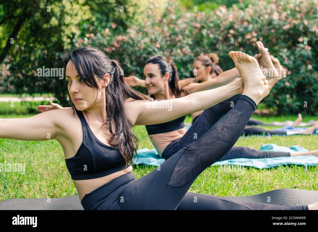 Konzentrierte und lächelnde Mädchen machen Yoga im Park Stockfoto
