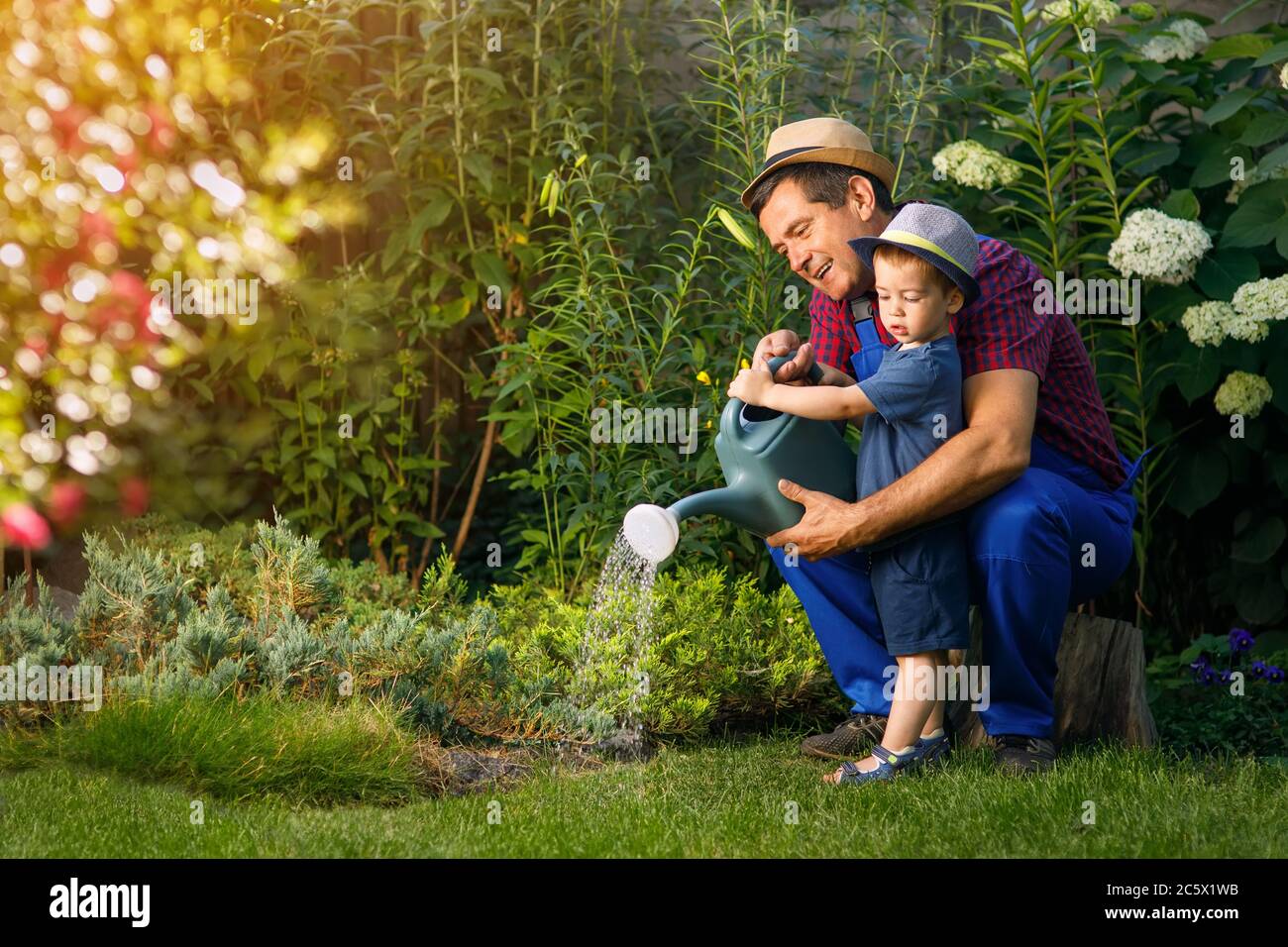 Mann Gärtner mit Enkel Bewässerung Garten Stockfoto