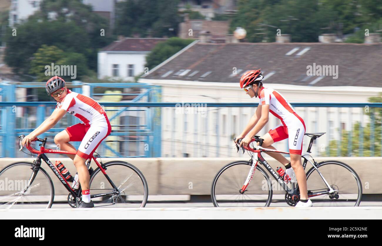 Belgrad, Serbien - 4. Juli 2020: Zwei Teenager-Jungen aus dem gleichen professionellen Team-Training, Fahrrad auf der Stadtstraße Brücke fahren Stockfoto