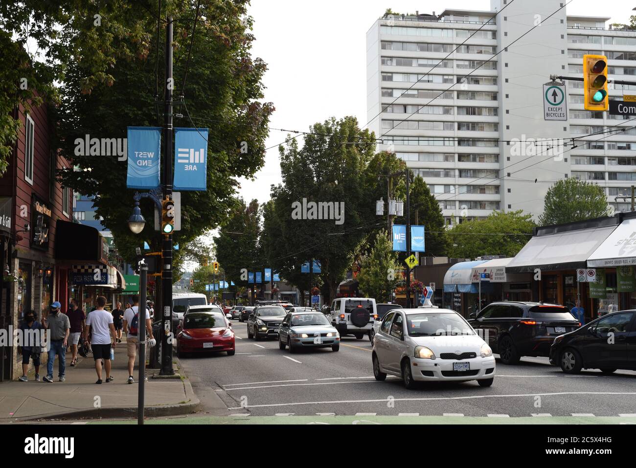 Ein Blick auf die Denman Street in der Comox Street im West End von Vancouver, British Columbia, Kanada, zeigt Verkehr, Fußgänger, Geschäfte und eine Wohnung Stockfoto