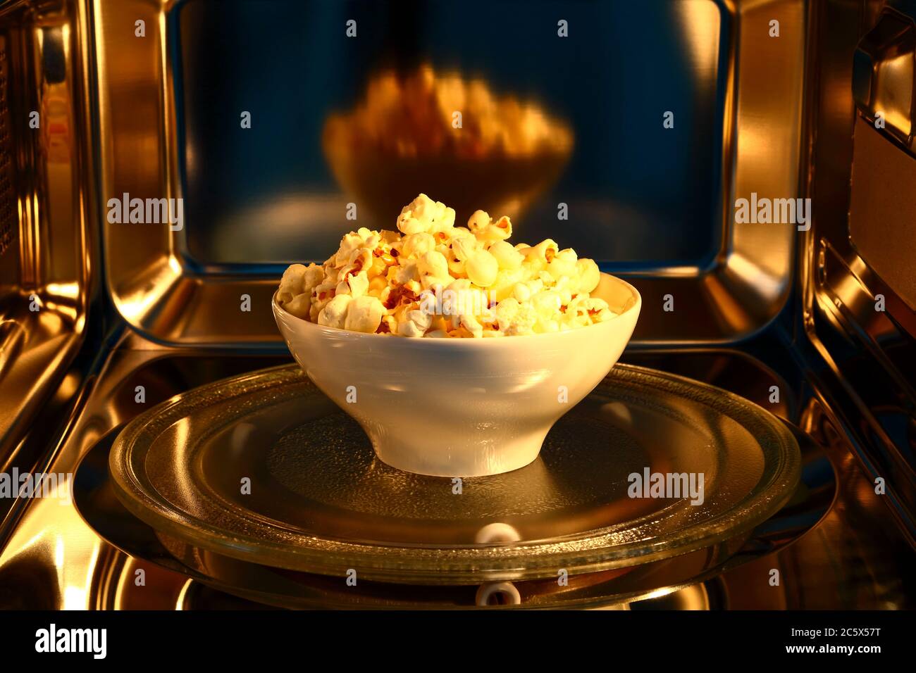 Schüssel Popcorn in der Höhle eines Edelstahl-Mikrowellenofens Stockfoto