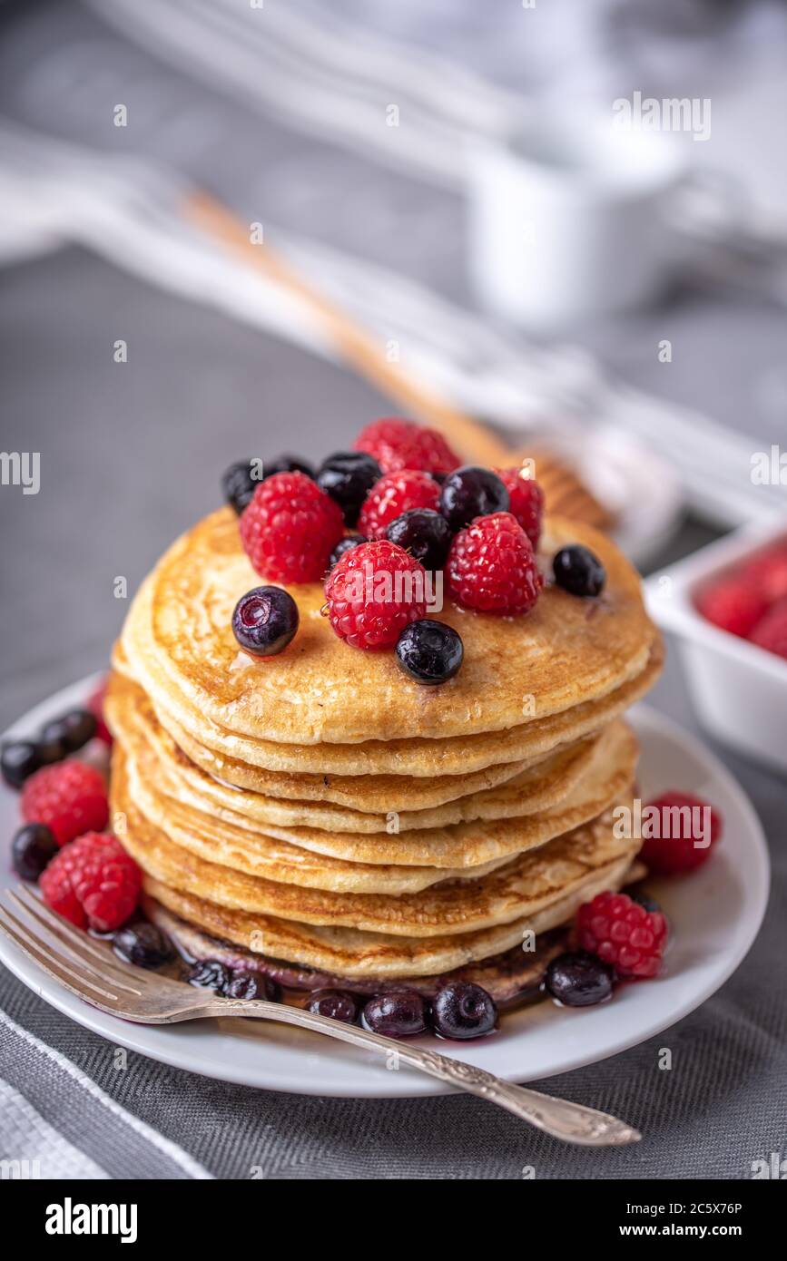 Hausgemachte Pfannkuchen mit Himbeeren und Heidelbeeren auf grauer Serviette. Stockfoto