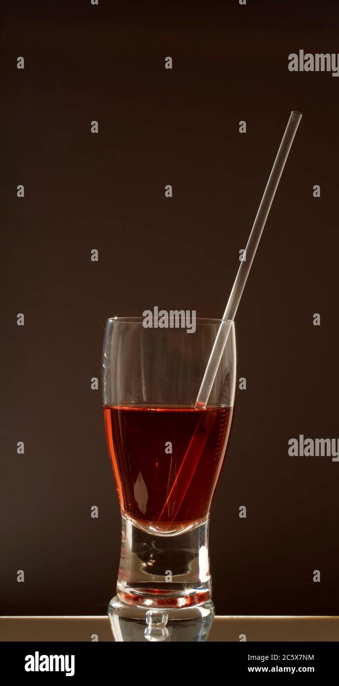 Glas mit Stroh und roter Flüssigkeit Stockfoto