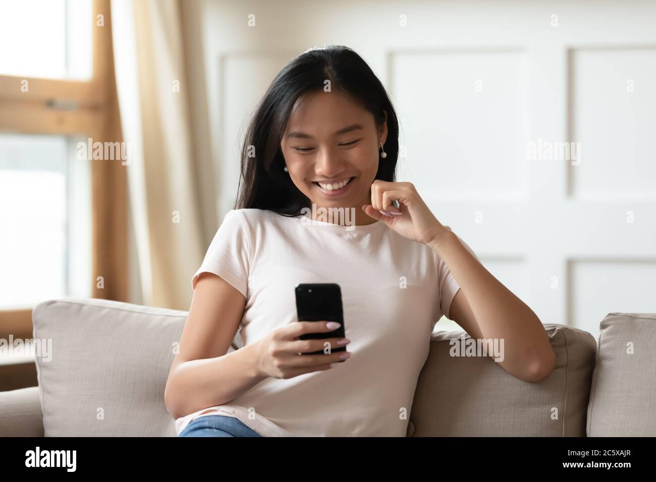 Glücklich aufrichtig junge asiatische Frau Blick auf mobile Bildschirm. Stockfoto