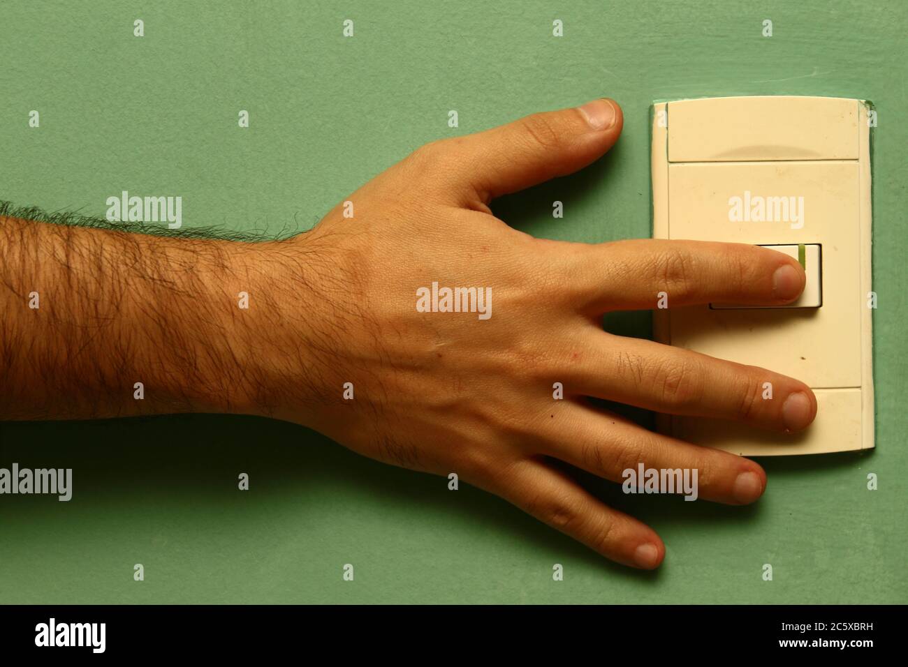 Hand des Mannes berühren elektrischen Schalter auf einem hellgrünen Hintergrund Stockfoto