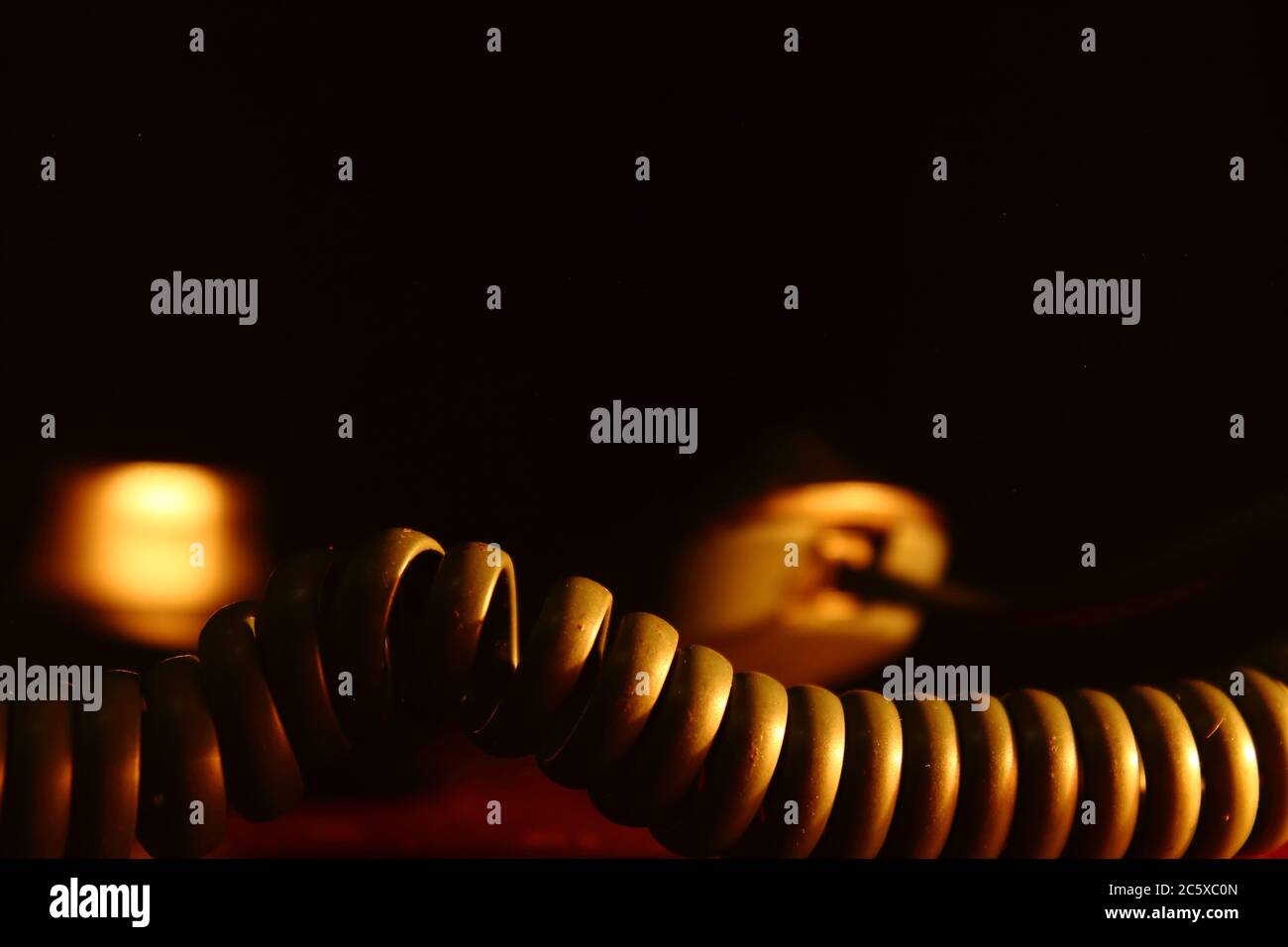 Telefonkabel mit Ohrhörer im Hintergrund bei warmer Beleuchtung Stockfoto