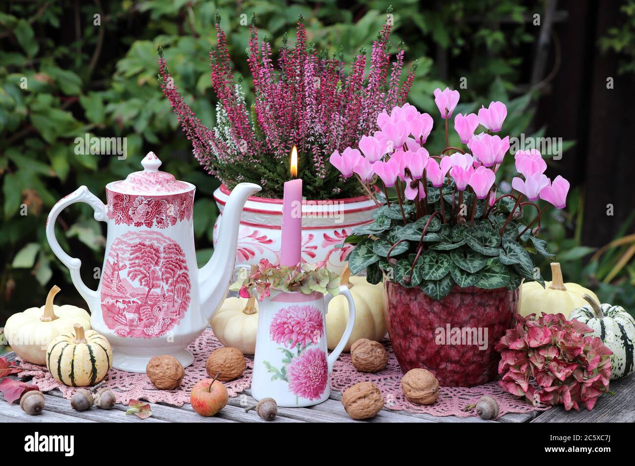 Herbstgartendekoration mit Kerze, Cyclamen und Heidekraut Blumen und Vintage Porzellan Stockfoto