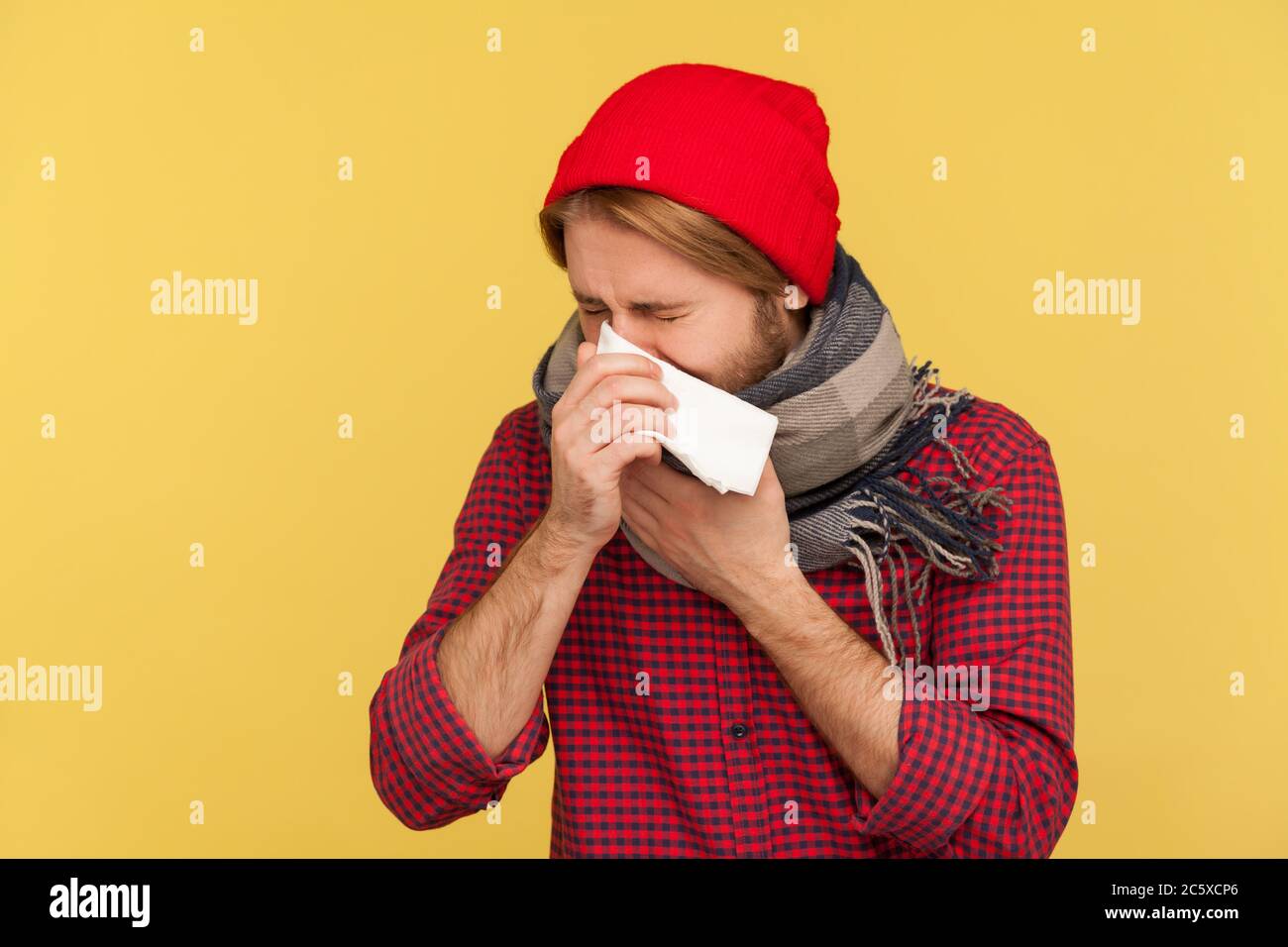 Kranker Kerl in Hut und warmen Schal hustet niesen Serviette, Gefühl unwohl mit laufender Nase, Halsschmerzen, leiden Allergie oder saisonale Grippe-Symptome Stockfoto