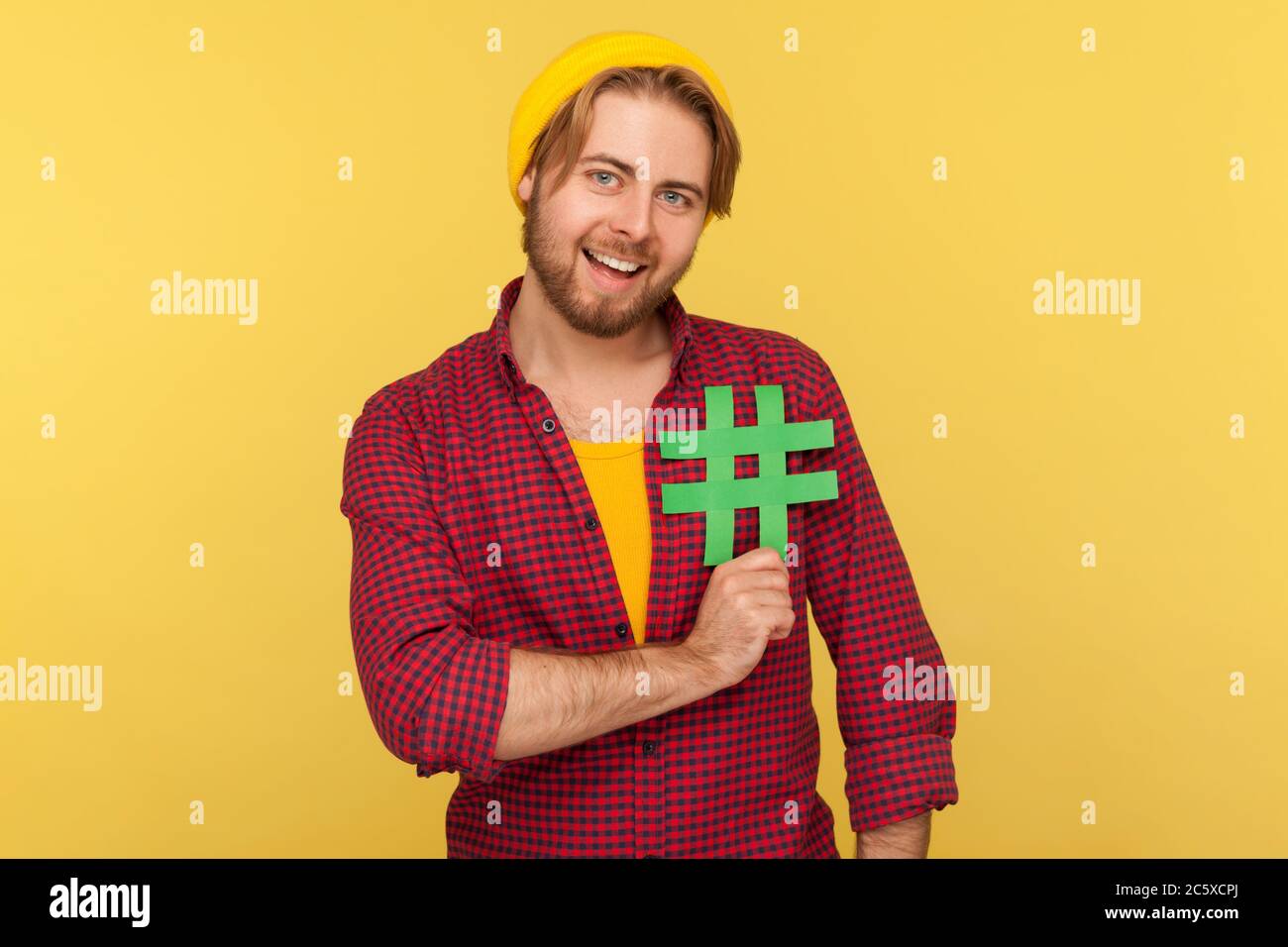 Hashtag, Internet-Trends. Positive Hipster Kerl in karierten Hemd lächelnd und halten Hash-Zeichen auf seiner Brust, Symbol der viralen Nachricht sozialen Netzwerk. Stockfoto