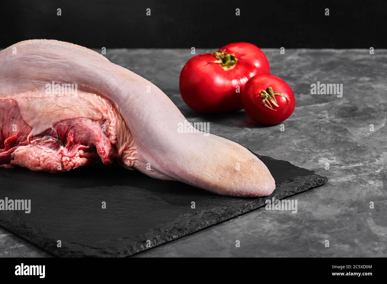 Rohe Rindfleischzungen auf dunklem Hintergrund Stockfoto