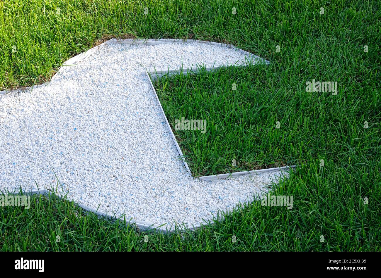Weißes Schraubenschlüssel-Symbol aus Steinen auf grünem Gras. Sommer. Konzept für grüne Industrie und Arbeit Stockfoto