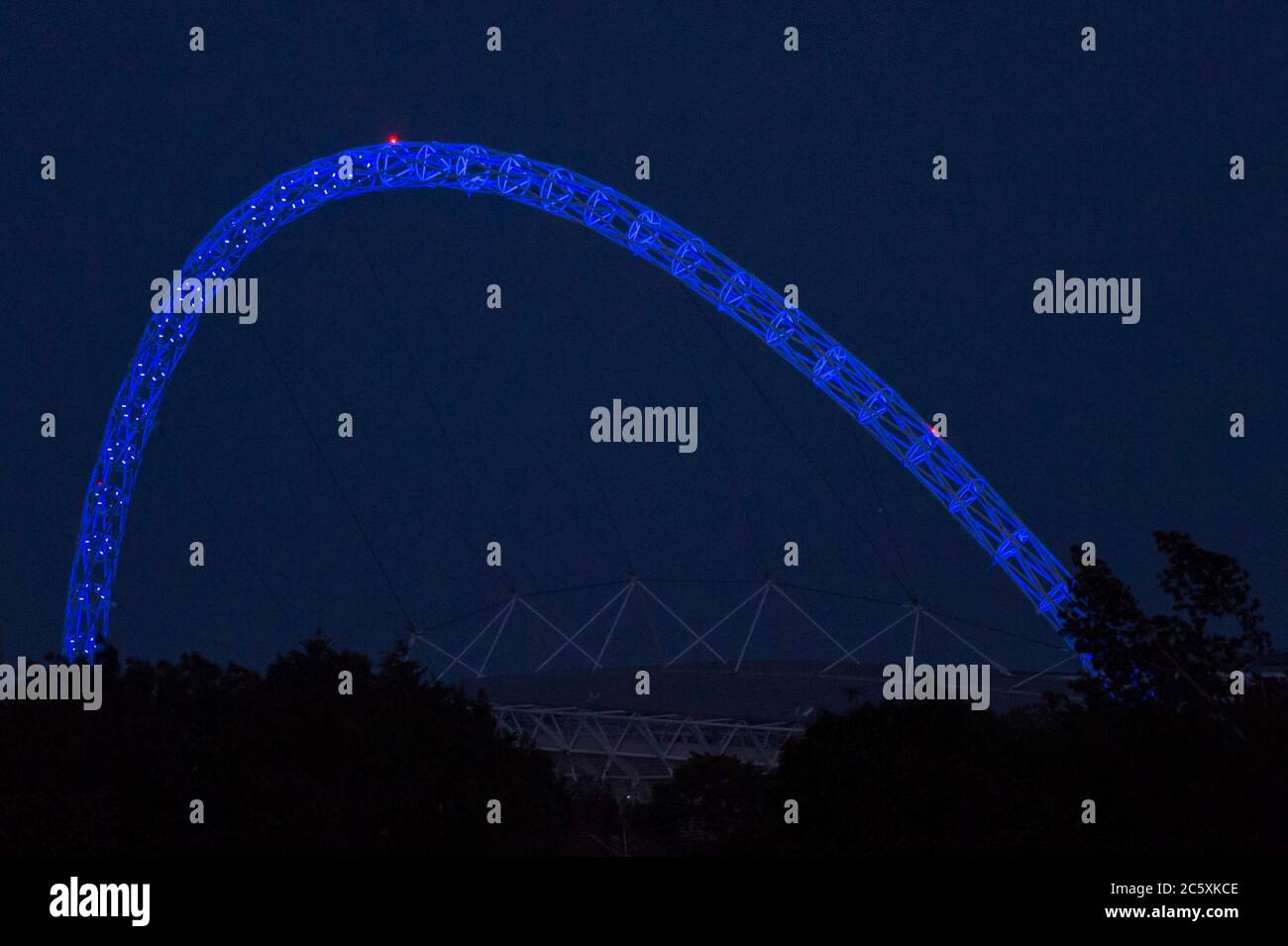 Wembley, Großbritannien. Juli 2020. Wetter in Großbritannien - der Bogen des Wembley-Stadions ist blau beleuchtet, um den 72. Geburtstag des National Health Service (NHS) zu feiern und allen NHS-Mitarbeitern für ihre Bemühungen während der laufenden Coronavirus-Pandemie zu danken. Der Vollmond des Juli, bekannt als Buck Moon, wird sich hinter dem Wembley Stadium im Nordwesten Londons erheben. Im Bauernalmanach ist der Buck Moon so benannt nach dem neuen Geweih, das um diese Jahreszeit aus der Stirn eines Bocks hervortritt. Kredit: Stephen Chung / Alamy Live Nachrichten Stockfoto