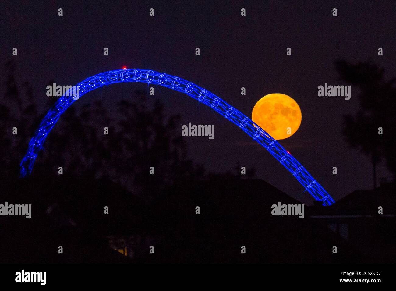 Wembley, Großbritannien. Juli 2020. UK Wetter - der Vollmond des Juli, bekannt als Buck Moon, erhebt sich hinter dem Wembley Stadium im Nordwesten Londons. Im Bauernalmanach ist der Buck Moon so benannt nach dem neuen Geweih, das um diese Jahreszeit aus der Stirn eines Bocks hervortritt. Der Bogen des Stadions ist blau beleuchtet, um den 72. Geburtstag des National Health Service (NHS) zu feiern und allen NHS-Mitarbeitern für ihre Bemühungen während der laufenden Coronavirus-Pandemie zu danken. Kredit: Stephen Chung / Alamy Live Nachrichten Stockfoto