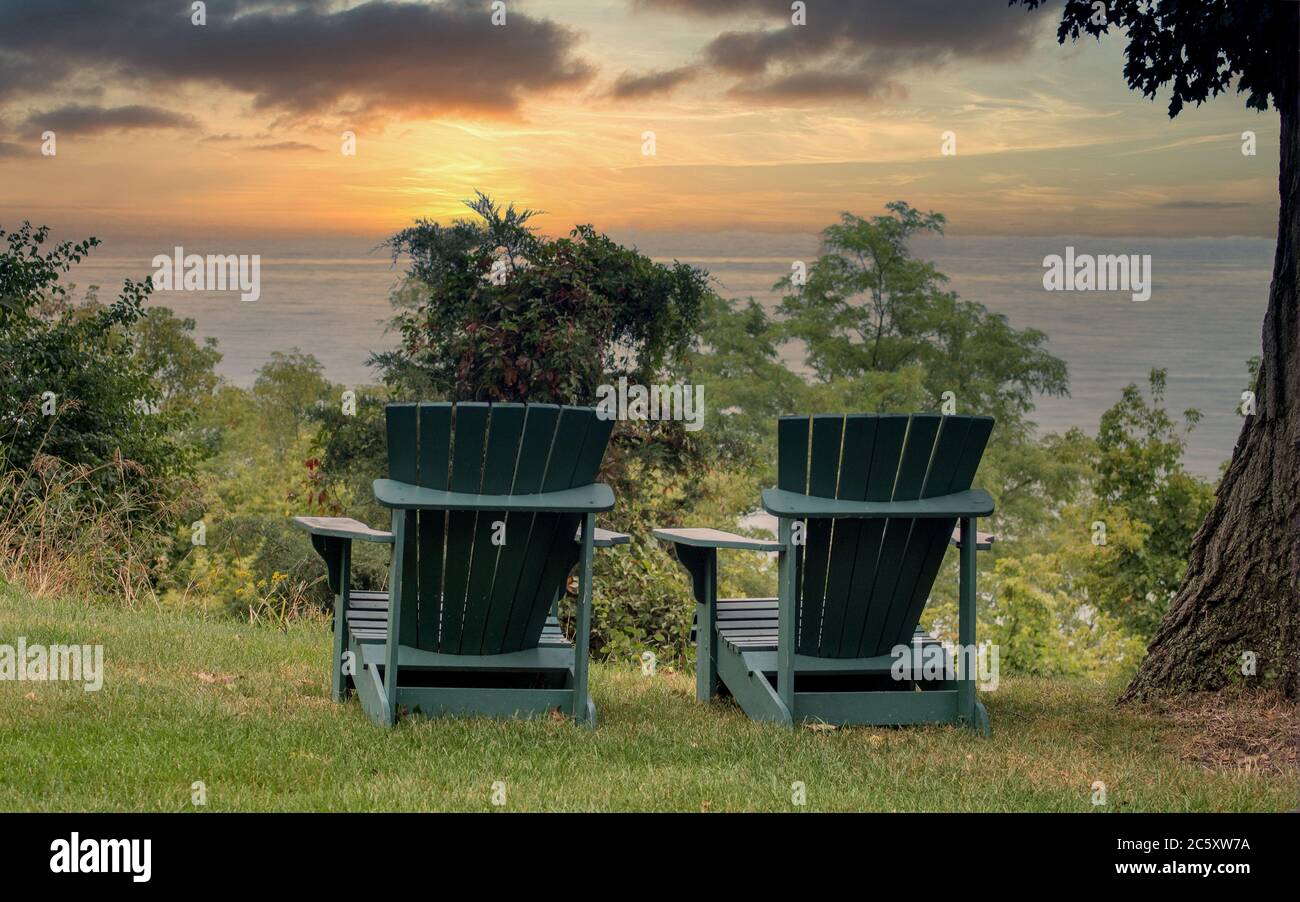 Ein Paar Adirondack Stühle sitzen auf einer Klippe mit Blick auf Lake Michigan in Michigan USA, mit einem schönen Sonnenuntergang Stockfoto