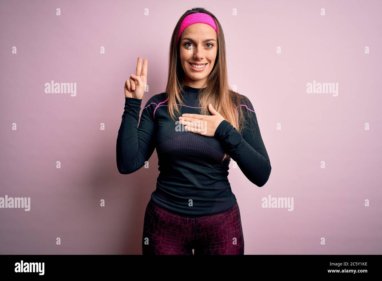 Junge blonde Fitness-Frau trägt Sport-Workout-Kleidung über isolierten Hintergrund lächelnd Fluchen mit Hand auf Brust und Finger nach oben, so dass eine Loyalität Stockfoto