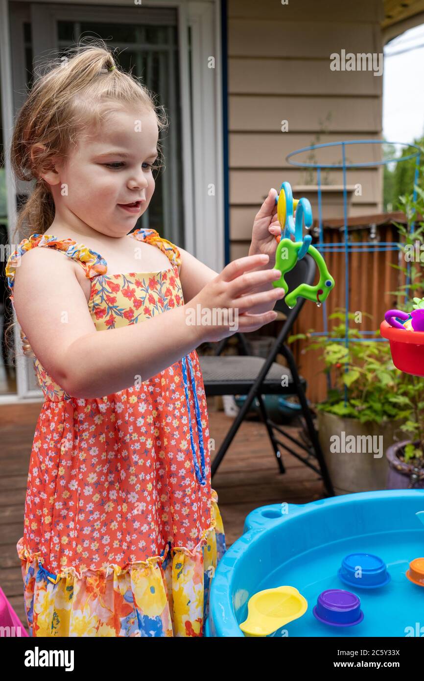 Drei Jahre altes Mädchen mit Spaß mit ihr außerhalb Wasser Spielzeug. Sie hat einen Frosch auf ihrer Angelrute gefangen! Stockfoto