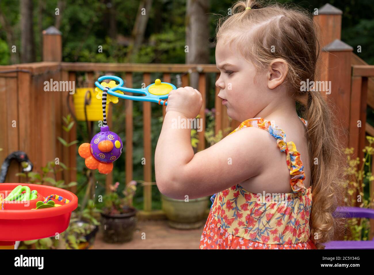 Drei Jahre altes Mädchen mit Spaß mit ihr außerhalb Wasser Spielzeug. Sie hat ein Spielzeug mit ihrer Angel 'Rute' gefangen. Stockfoto