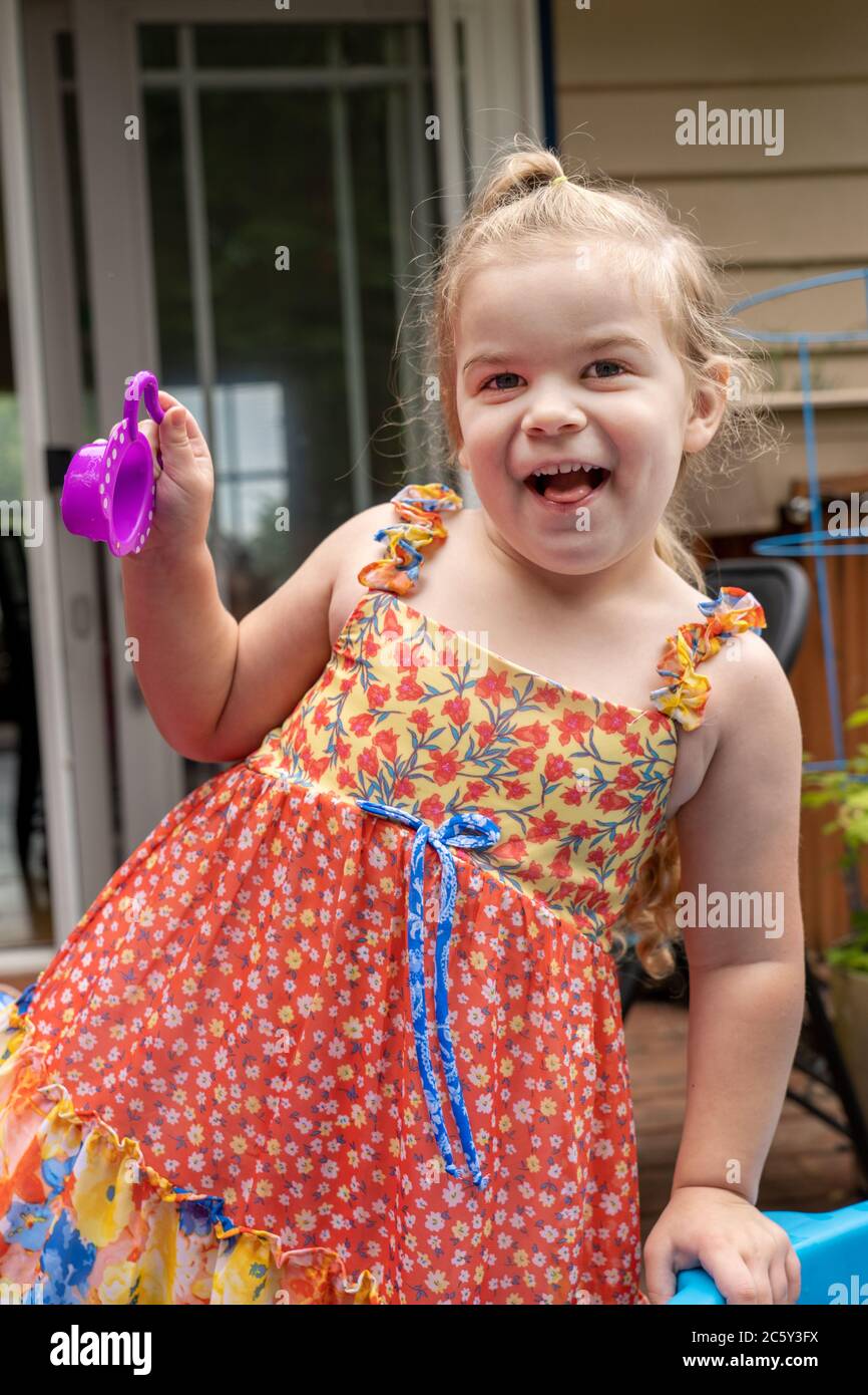 Drei Jahre altes Mädchen mit Spaß spielen draußen mit ihr Wasser Spielzeug. Stockfoto