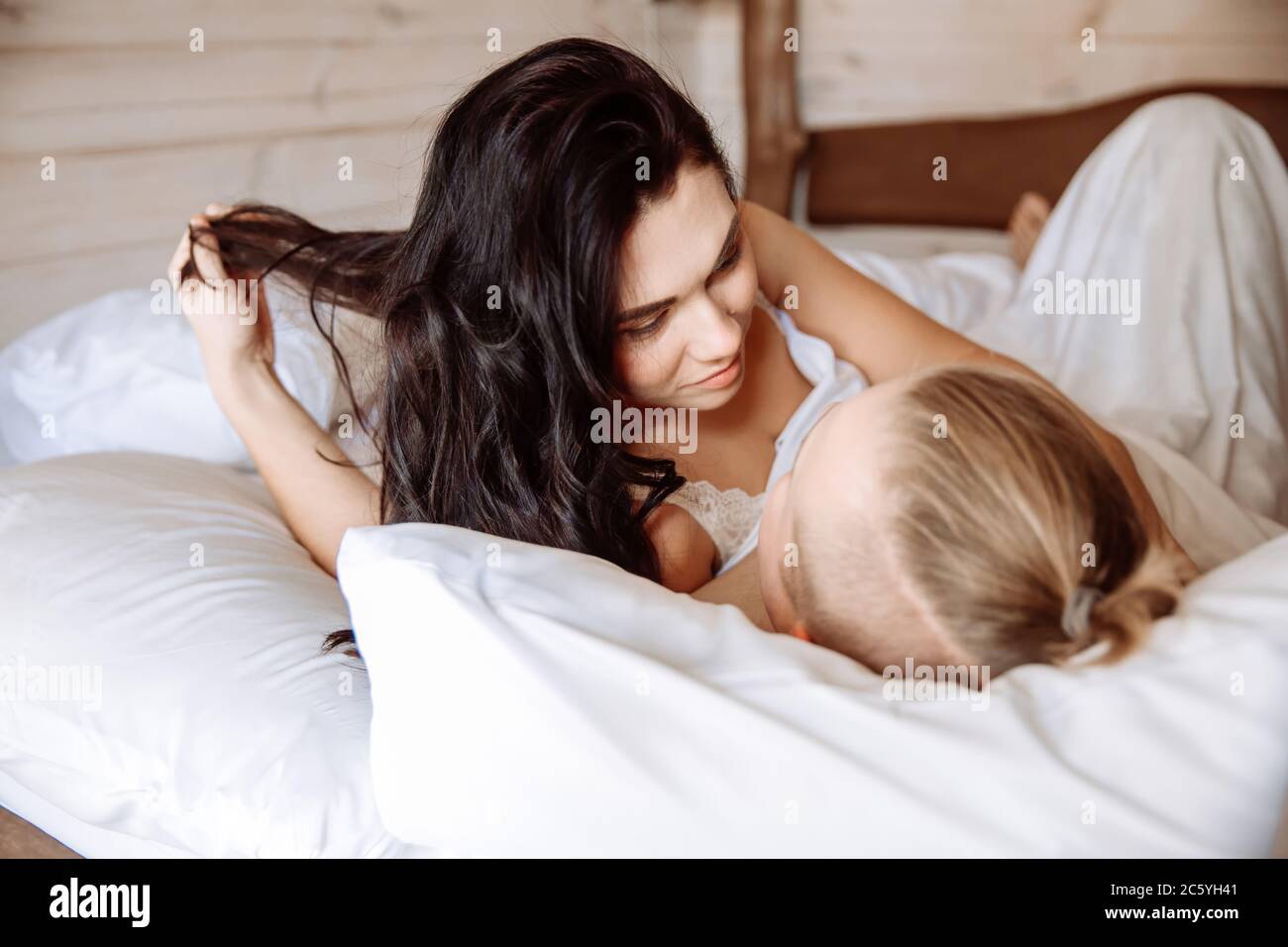 Ein junger Mann und eine junge Frau sonnen sich im Bett zusammen. Sie liegen unter weißen Laken. Ein liebevolles Paar wachte gerade auf. Stockfoto