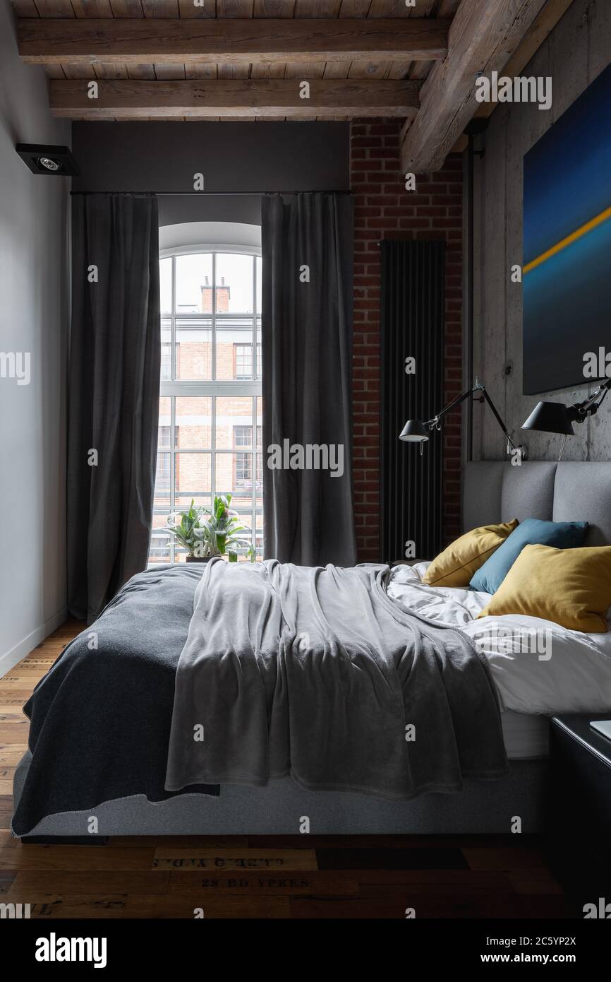 Schlafzimmer im Industriestil mit moderner Malerei und grauen Fenstervorhängen Stockfoto